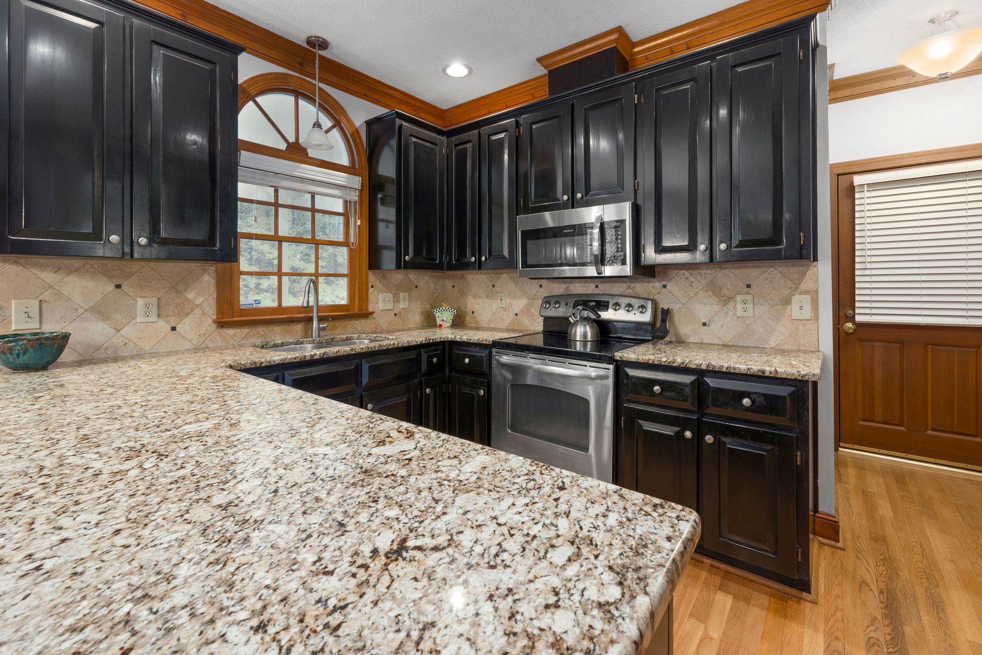 Sleek kitchen with dark cabinets, granite countertops, and stainless steel appliances.